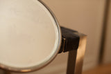 Detail of the antique shaving mirror's aged, patinated glass surface and thin frame.