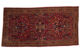 Vintage Sarouk rug runner with a central palmette medallion on a raspberry field of stylized floral sprays.