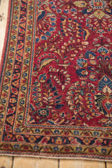 Close view of a Sarouk's serrated leaf and meandering vine borders in raspberry, blue, and gold.