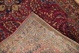 Folded corner of a vintage Sarouk rug revealing its hand-knotted foundation and raspberry pile.
