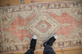 Faded brick red and sand distressed Oushak runner with diamond medallion.