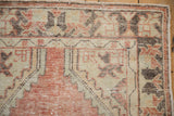 Distressed Oushak rug corner, faded brick red, ivory, brown spandrel, and worn pile.
