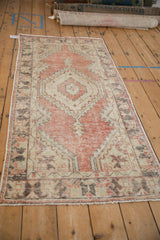 Detail of distressed Oushak rug: faded brick red diamond, ivory, seafoam spandrel with splayed florals, pile wear.