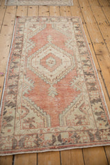 Faded brick red, ivory, dark brown distressed Oushak runner with visible knot head wear.