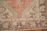 Distressed border detail of Oushak runner with faded brick red, ivory, and visible pile wear.
