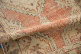 Folded vintage distressed Oushak runner showing faded brick red and ivory patterns with worn pile.