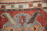 Decorative detail of distressed Oushak rug, cherry red abrash and seafoam green leaves.