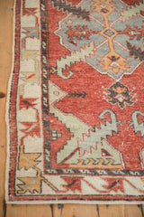 Distressed Oushak runner's side border, featuring geometric patterns and worn red, green pile.