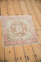 Full angled view of a distressed Oushak square mat showing its faded pink and copper pattern.