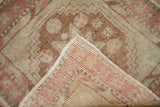 Folded corner of a distressed Oushak rug reveals its hand-knotted foundation and low pile.