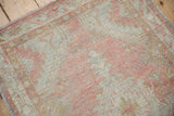Distressed Oushak runner's textured pile, with visible foundation and soft pale blush, oxidized silver tones.