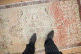 Downward view highlighting the distressed texture and sandalwood to copper tones of a vintage runner.
