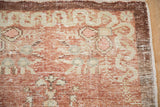 Worn, hand-knotted texture at the corner of a distressed rug with a brown border.