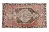 A distressed vintage Oushak rug featuring a scalloped medallion in bronze, ivory, and faded mauve.