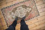 Overall pattern and worn texture of a distressed Oushak rug in olive green and faded mauve.