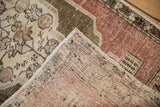 Folded corner of a vintage Oushak rug showing its woven back, texture, and secured side cord.