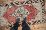 Distressed vintage Oushak runner with abrashed brick red field and pale seafoam medallion.