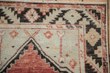 Distressed Oushak runner corner, brick red, charcoal geometric patterns on abrashed pale seafoam.