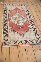 Distressed vintage Oushak rug corner, showing serrated geometric border, faded brick red, and even wear.