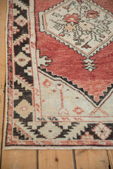 Distressed Oushak rug corner showing pale fringe, serrated spandrel, and charcoal border.