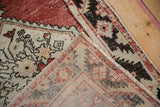 Folded detail of distressed Oushak rug with brick red and pale seafoam green serrated patterns.