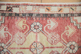 Detail of a distressed Turkish Oushak rug corner showing floral wheel elements and a charcoal border.