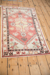 Angled view of a distressed Oushak rug, showing its brick red stepped medallion and charcoal accents.