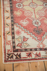 Corner detail of a distressed Oushak rug with stepped spandrels and low pile in brick red and charcoal.