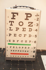 Graham Field eye exam light box displaying a cream chart with brown letters, green and red lines.