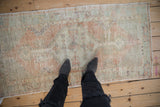 A person standing on a vintage distressed Oushak runner, highlighting its soft, worn texture.