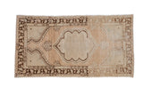 Vintage distressed Oushak rug with a scalloped medallion on an abrashed field of beige, ivory, and brown.