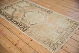 Angled view of a vintage Oushak rug highlighting its distressed low pile and scalloped brown medallion.