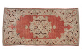 Distressed Turkish Oushak runner with a central medallion featuring stylized floral vines in dusty red and ivory.
