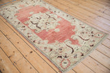 Vintage Turkish Oushak runner showing its distressed, low pile texture from an angled perspective.