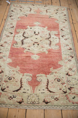 Vintage Oushak runner viewed from an angle, showing the abrashed red ground and time-softened texture.
