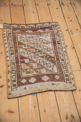 Distressed Kars rug corner with checkered border in aubergine, ivory, and saffron.