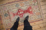 A standing view of the distressed Oushak rug, showing its scale and playful floral border.