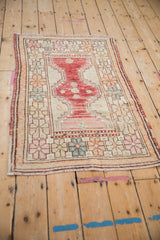 Angled view of a distressed Oushak rug highlighting its raspberry red central design and geometric floral border.