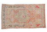 Vintage distressed Oushak rug with a shield medallion in seafoam green, pale cantaloupe, and silver.