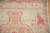 Corner detail of a vintage Oushak rug showing worn pile and alternating colors in the main border.