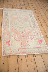 Angled view of a vintage Oushak rug showing its distressed texture and soft color variations.