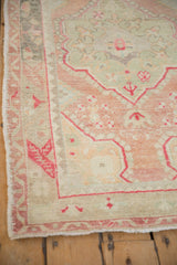 Angled view of the vintage Oushak rug's border showing alternating colors and intact side selvage.