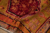 Plush pile texture of a vintage Oushak rug, showing red, orange, and aubergine floral motifs.