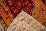 Textured vintage Oushak rug pile with red and orange tones, revealing its hand knotted backing and fringe.