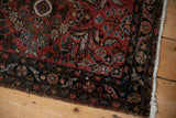 Vintage Dargezine rug corner, showing dark arabesque floral border and intact selvage.