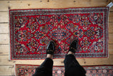 Vintage Sarouk runner's dense floral sprays in cherry red, navy blue, and ivory.