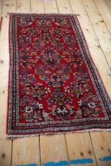 Close-up showing the Sarouk runner's rich cherry red field, detailed floral sprays, and meandering vine border.
