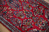 Cherry red Sarouk rug detail showing intricate floral sprays and patterned border.