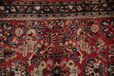A vintage Sarouk's detailed navy vine border and pinwheel florals on a cherry red field.