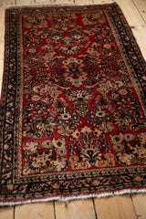 Vintage German Sarouk rug seen from an angle, featuring an allover floral pattern on a cherry red field.
